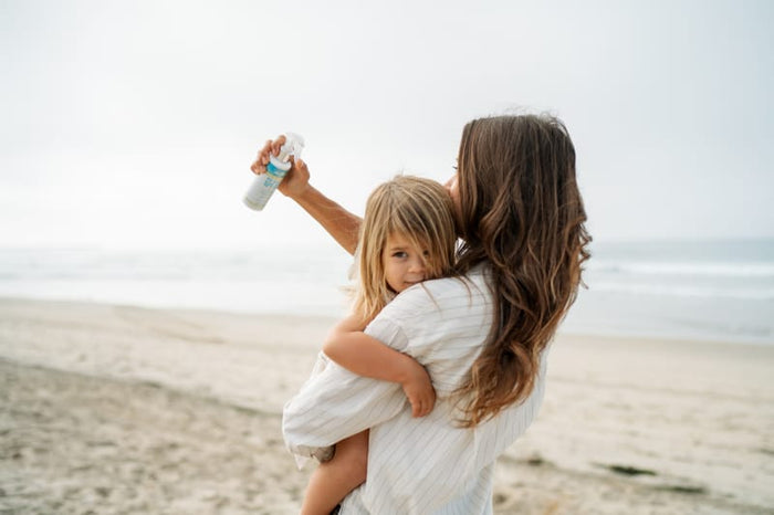 Mom carrying her daughter on the beach