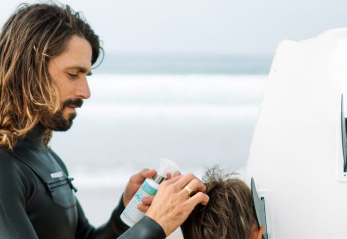 Man applying Active COCO to a child's hair on the beach